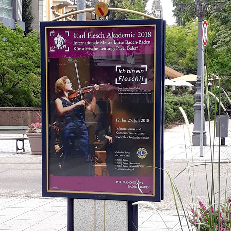 Das Plakat zum Abschlusskonzert 2018 hängt in der Fußgängerzone Baden-Baden.